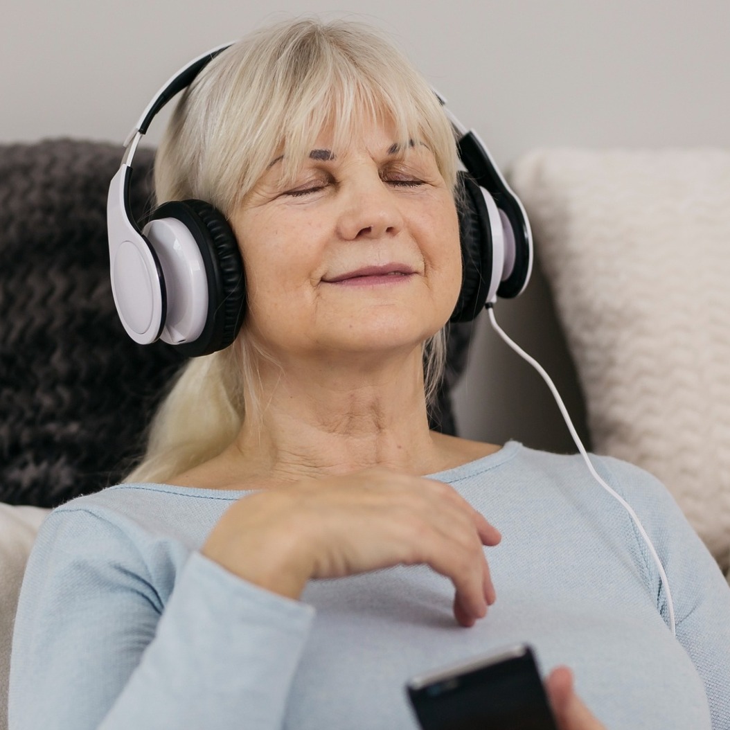 una mujer escuchando musica con el movil y los ojos cerrados, disfrutando del momento