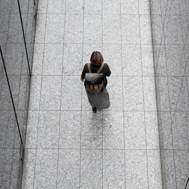 Una mujer caminando por un pasillo de espejos con una mochila de trabajo