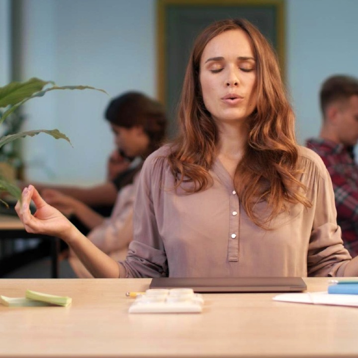 Una mujer con gesto de meditación en la oficina