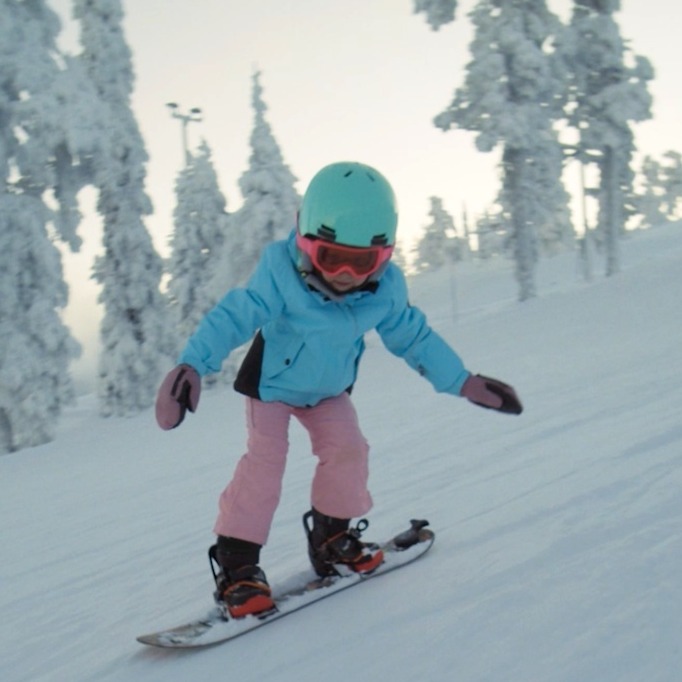 Una niña haciendo snowboard