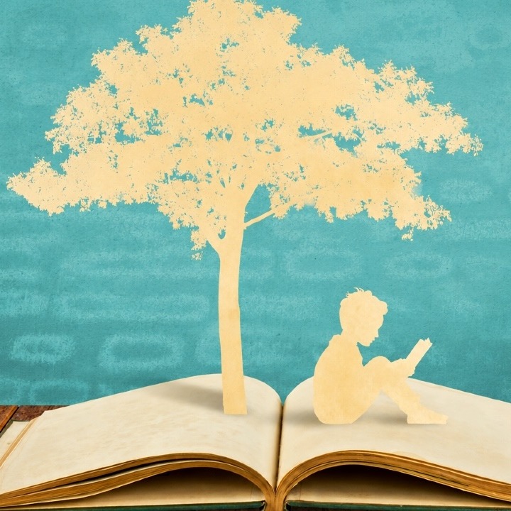 Un recorte de papel que sale de un libro y muestra la silueta de un árbol y un niño sentado leyendo