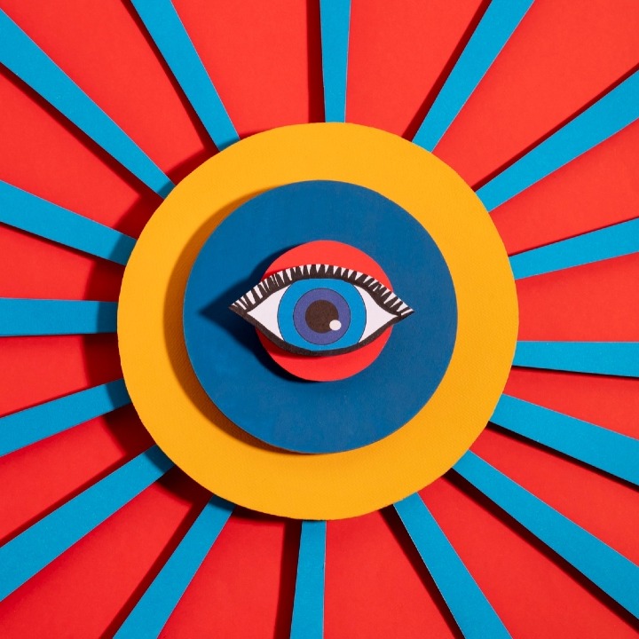 Un collage de colores con un ojo en el centro y líneas rojas y azules hacia los extremos