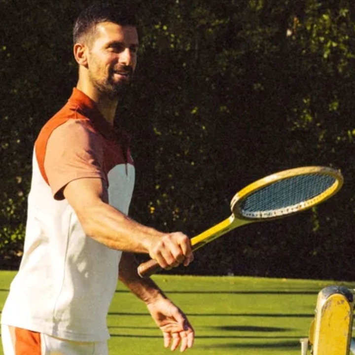 Novak Djokovic levantando una bolsa de Cob con una raqueta antigua de tenis