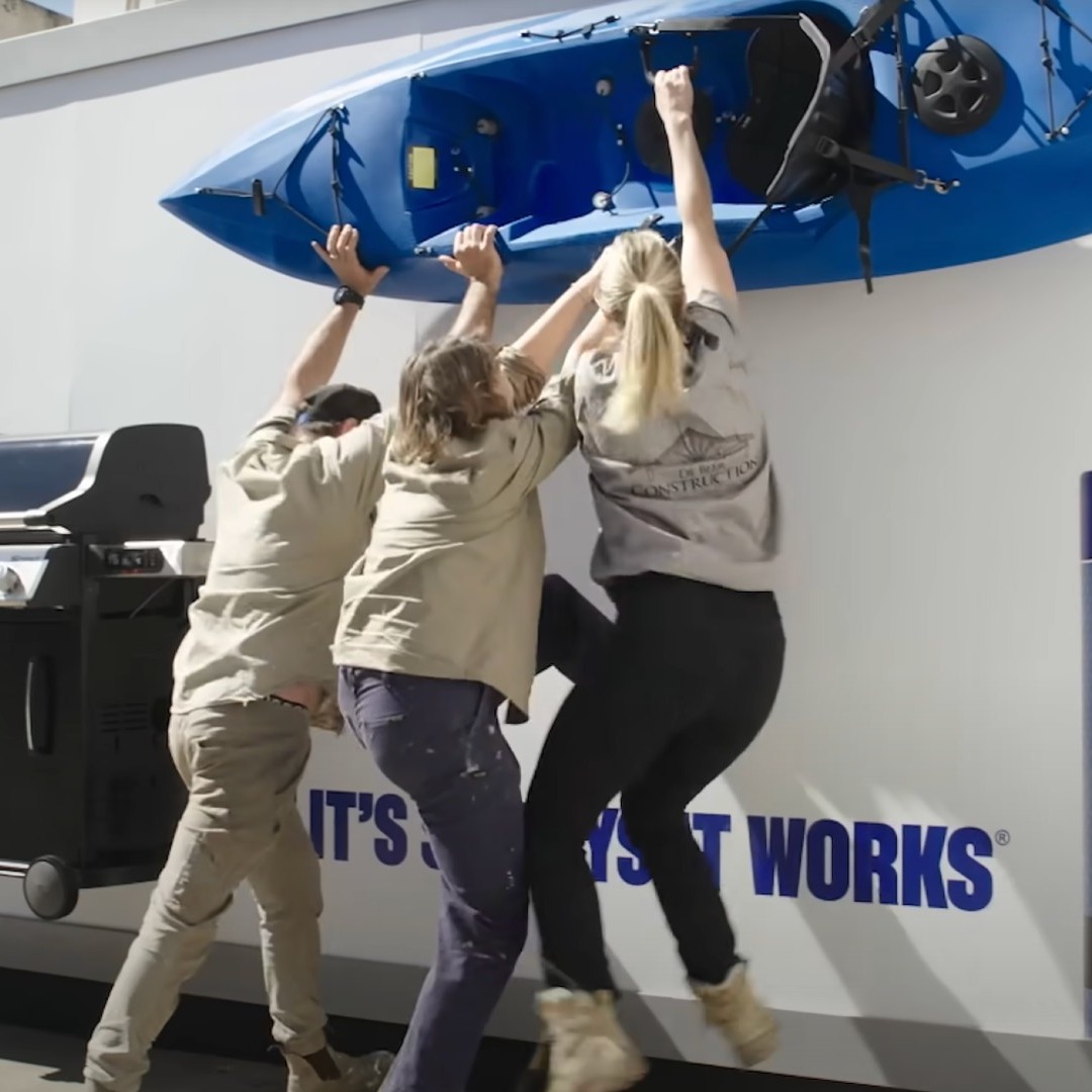 Tres personas intentando despegar un kayak de una pared