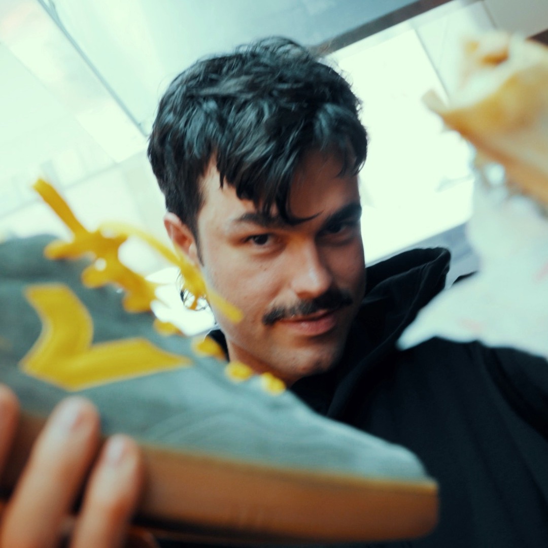 El tiktoker Peldanyos mirando a cámara mientras sujeta con una mano una zapatilla Victoria y con otra un shawarma