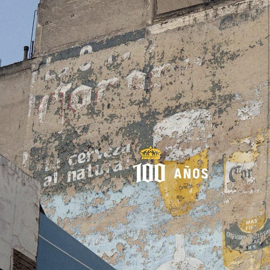 Fachada de edificio desgastada por el sol, con un anuncio de Coron