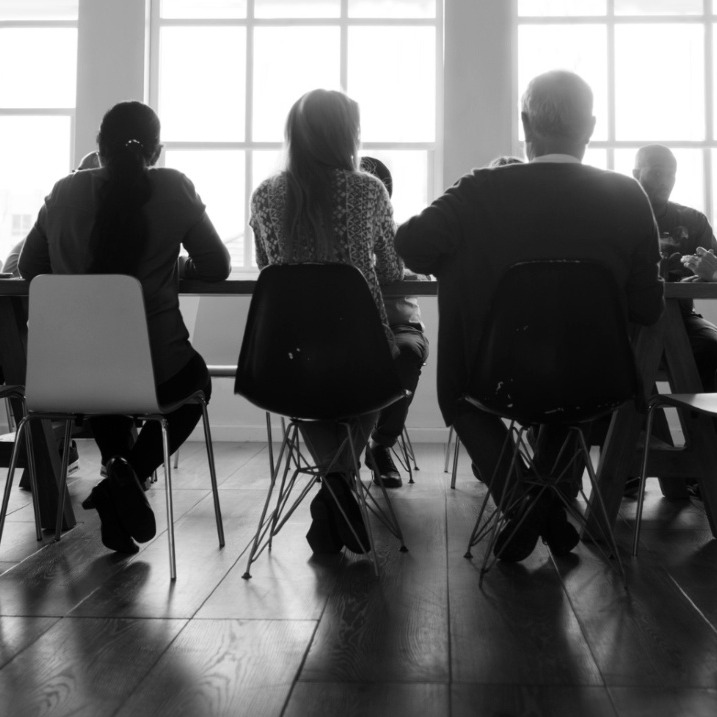 Una imagen en blanco y negro de personas reunidas en una mesa de oficina