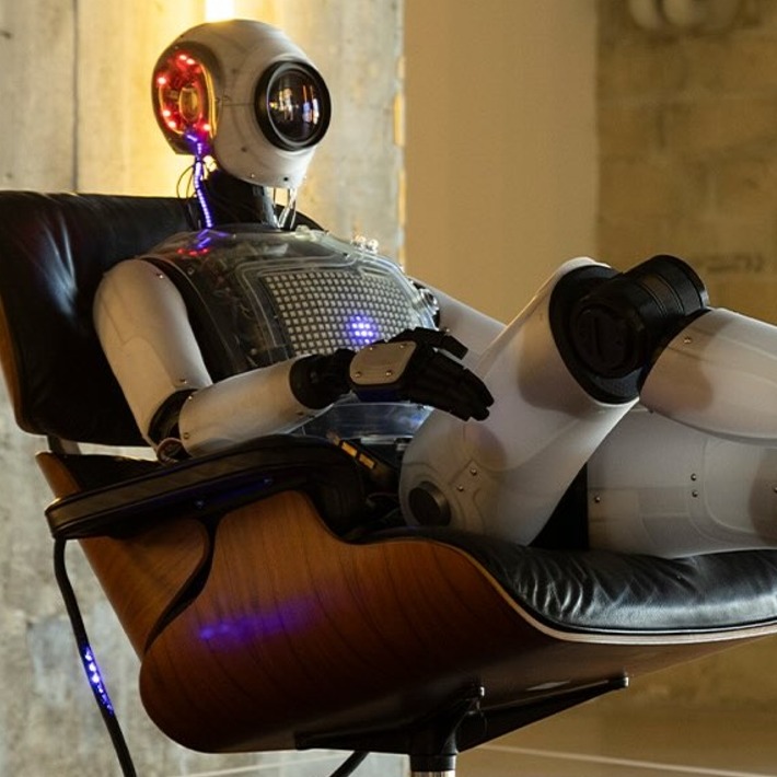 un robot sentado en un sillón viendo la televisión