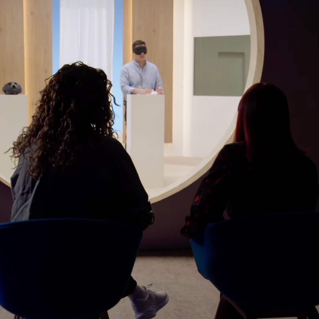 Dos mujeres miran a un hombre a través de una cámara