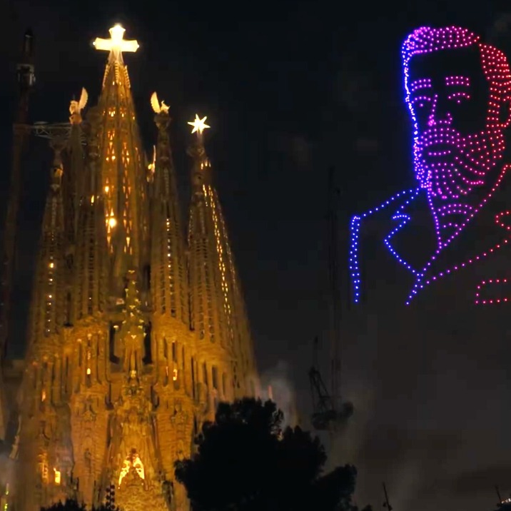 La Sagrada Familia iluminada y la imagen de Gaudí al lado hecha con drones