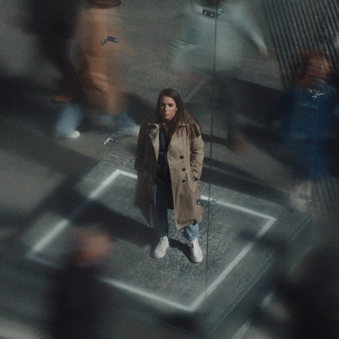 mujer sola en una caja de cristal entre la gente