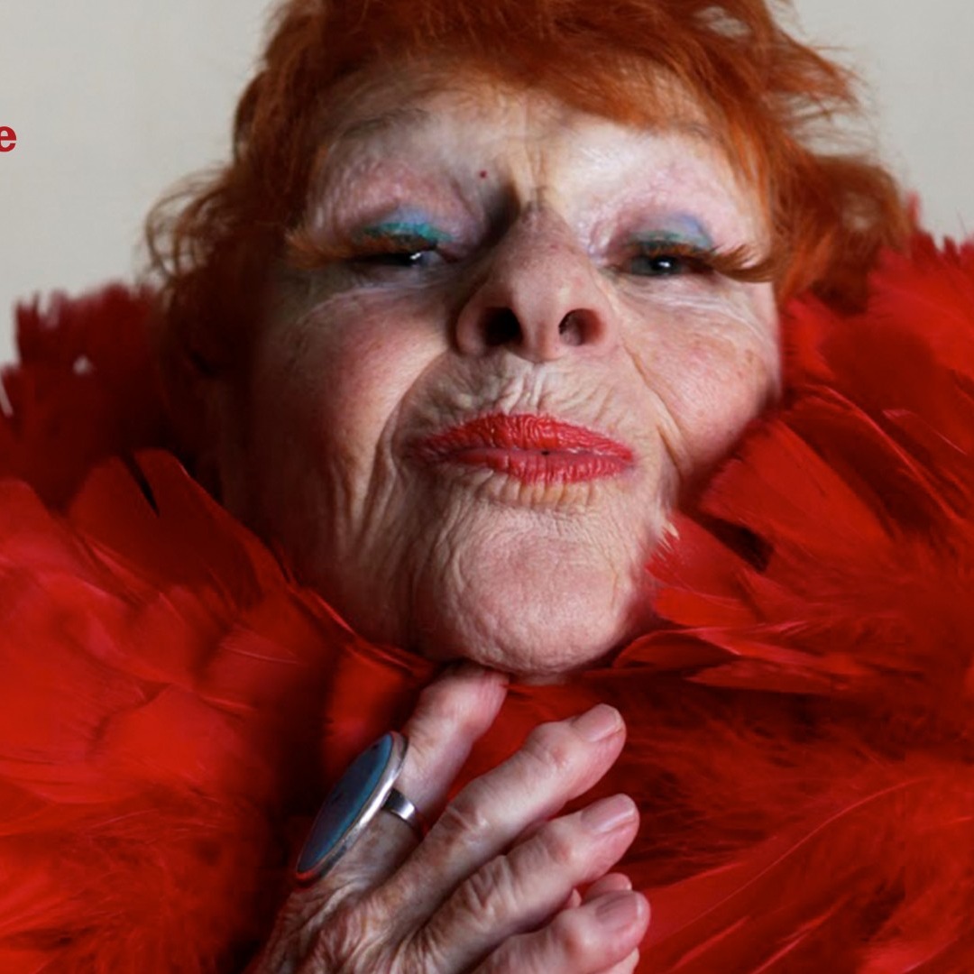 Una mujer mayor pelirroja con plumas rojas