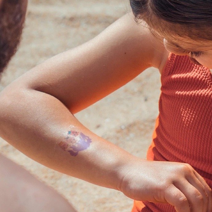 una niña mirándose el brazo con la calcomanía