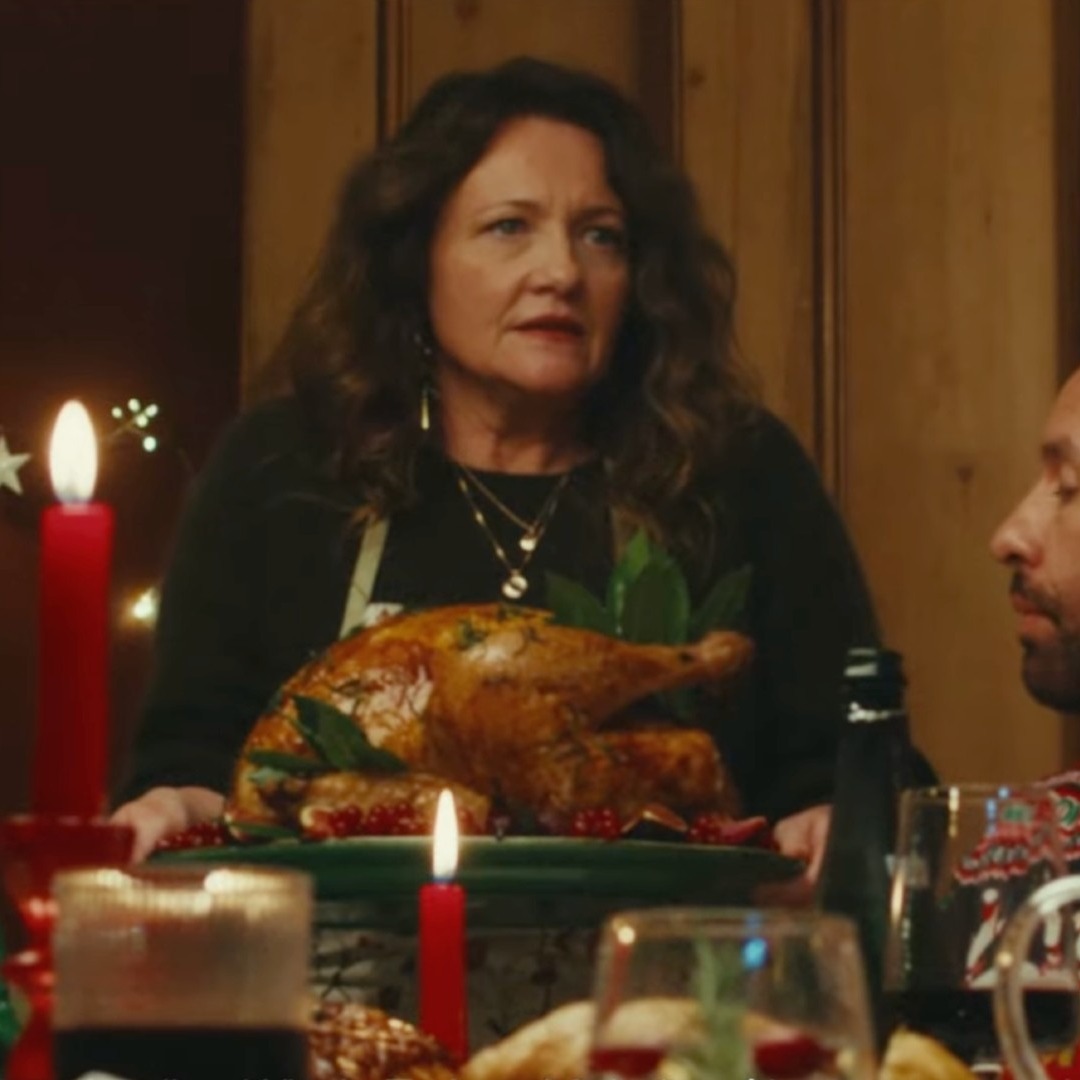 Una mujer sostiene un pavo en una cena de Navidad familiar