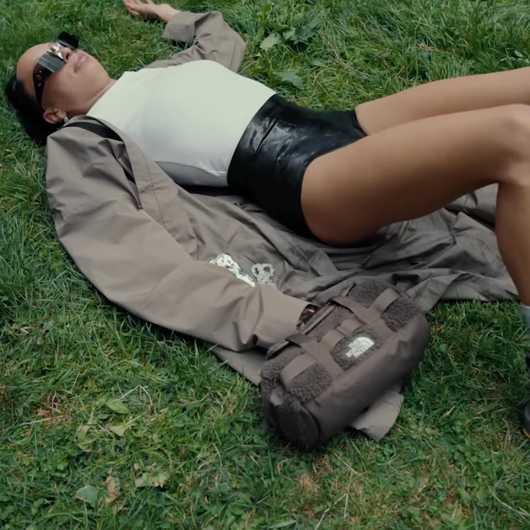 “Sal a tocar hierba”: la invitación de The North Face a la generación Z a conectar con la naturaleza Chica vestida con ropa de The North Face tumbada sobre hierba