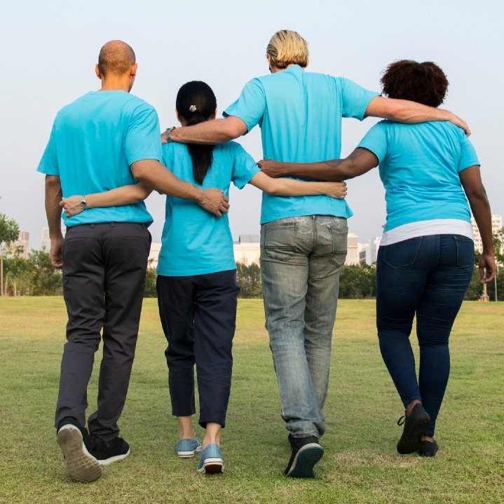 Un equipo de espaldas se abraza, vestidos todos con polos azules