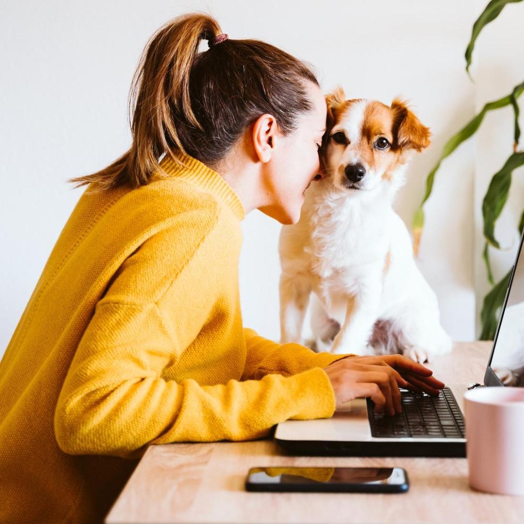 Mascotas y entorno laboral: la adopción de animales también llega a los permisos retribuidos Mujer trabajando junto a su perro