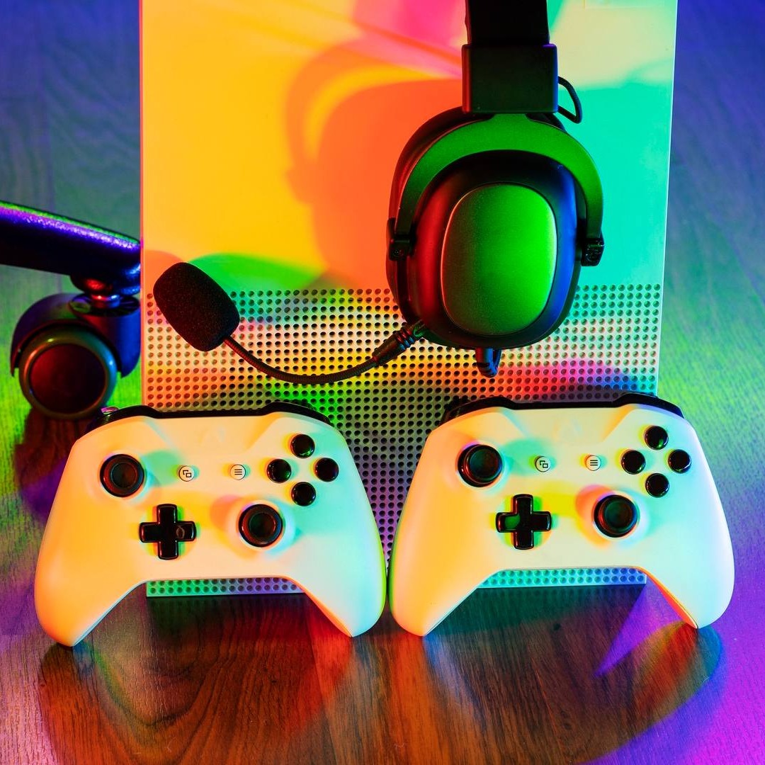 Dos mandos de Xbox en el suelo junto a la videoconsola
