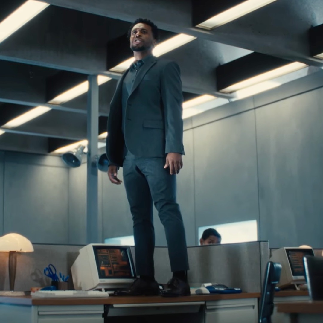 Un hombre de pie sobre un escritorio en una oficina gris