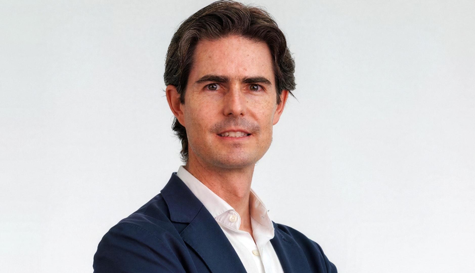 Un primer plano de Alejandro Guerra vestido con traje azul y camisa blanca