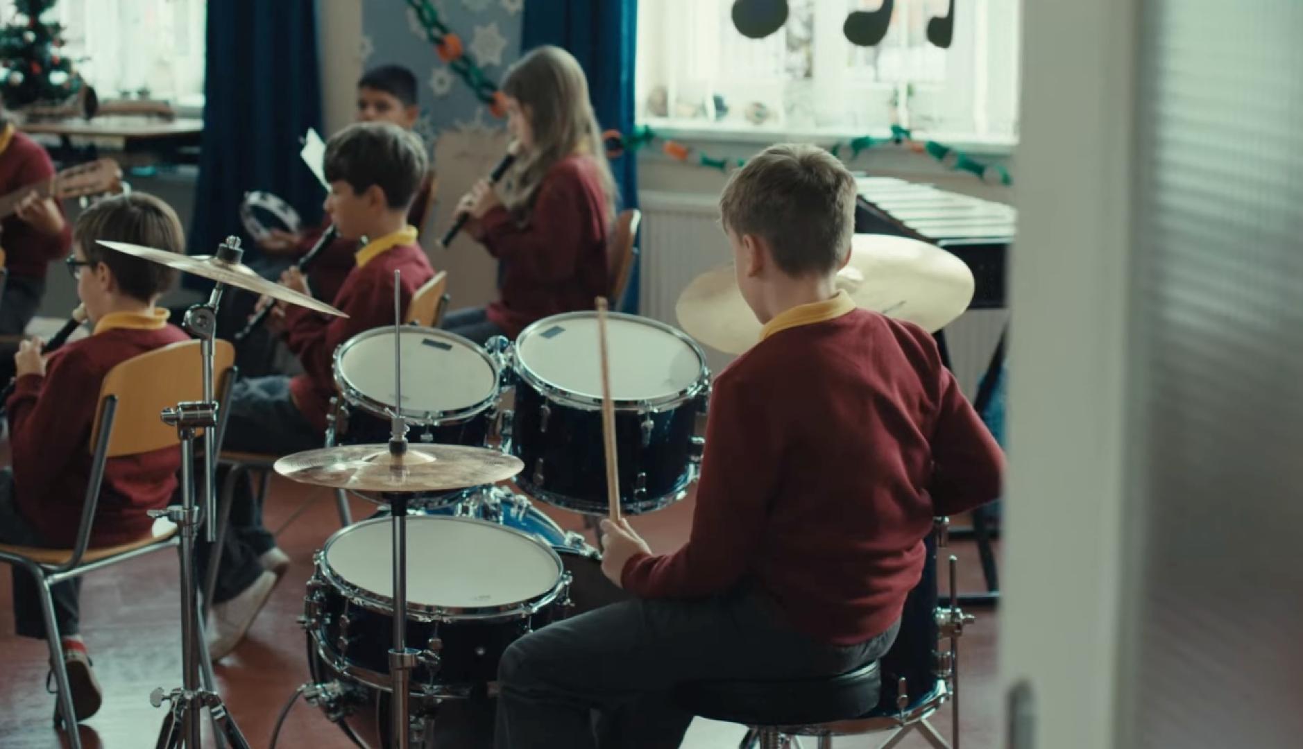 Un niño tocando la batería en una orquesta escolar