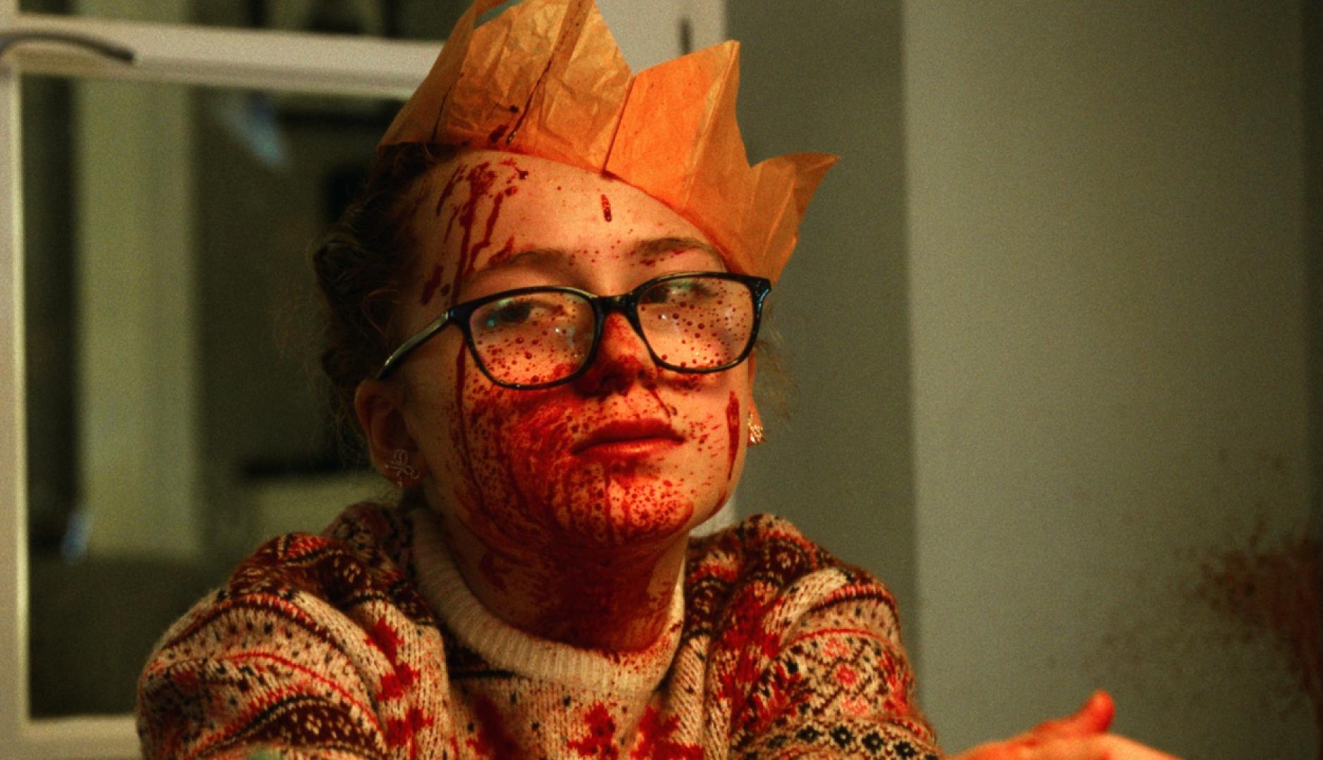 Una niña con corona de rey mago y la cara llena de sangre