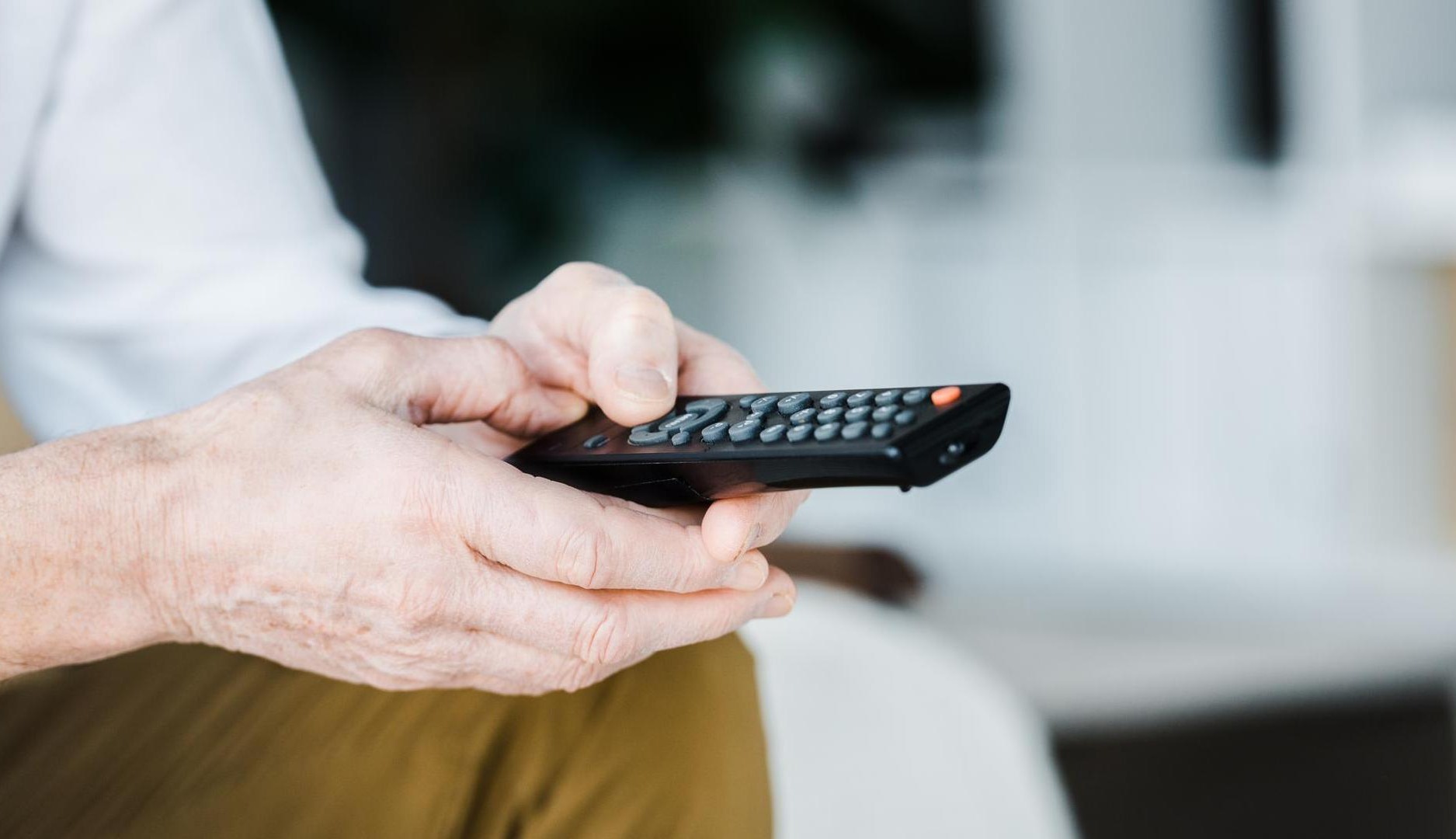 Manos sujetando un mando a distancia de televisión