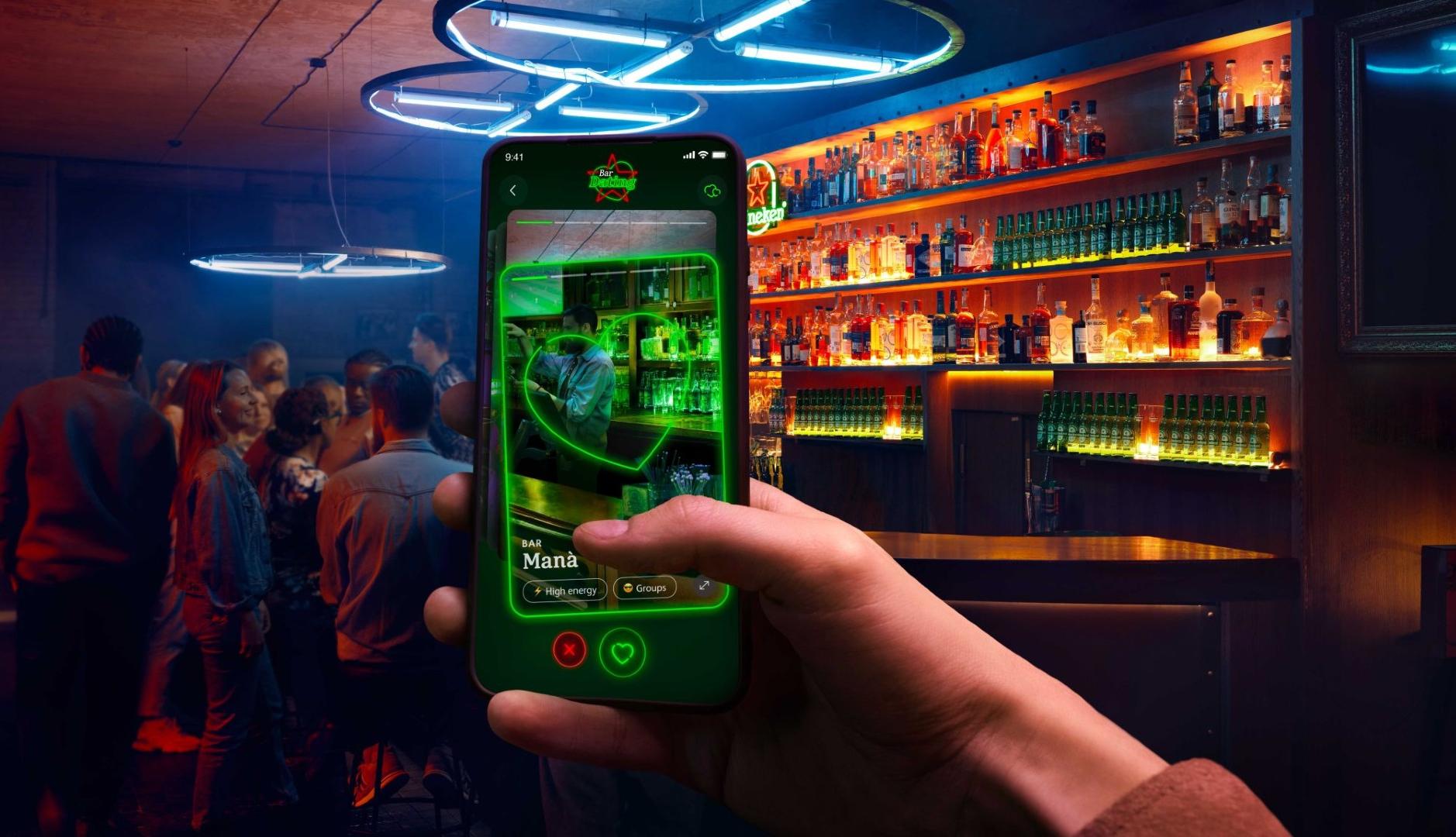 Nueva aplicación de Heineken para encontrar bares como si fueran citas románticas. Mano sosteniendo móvil en un bar