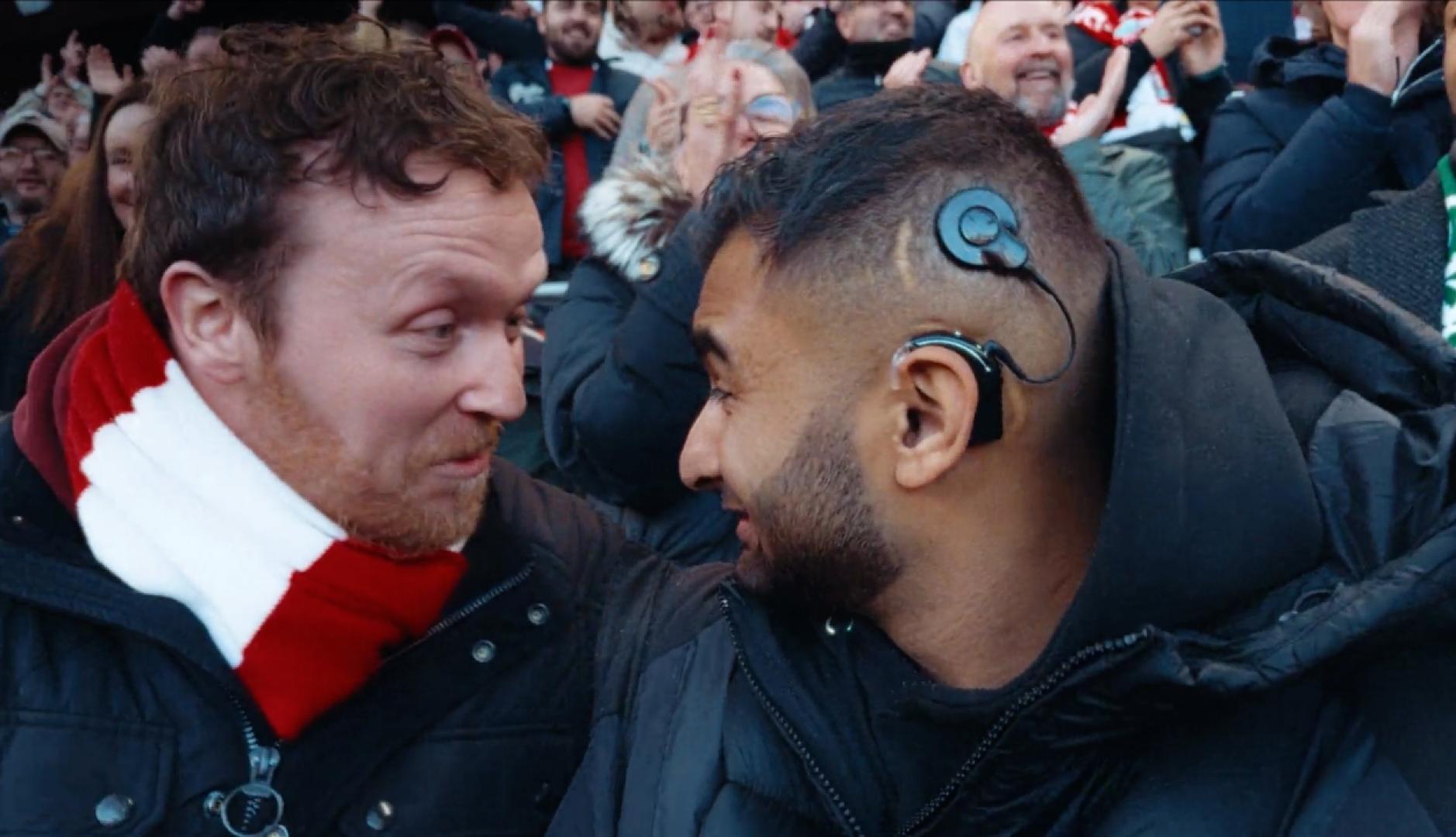 Dos aficionados se miran en el estadio, uno de ellos lleva un audífono