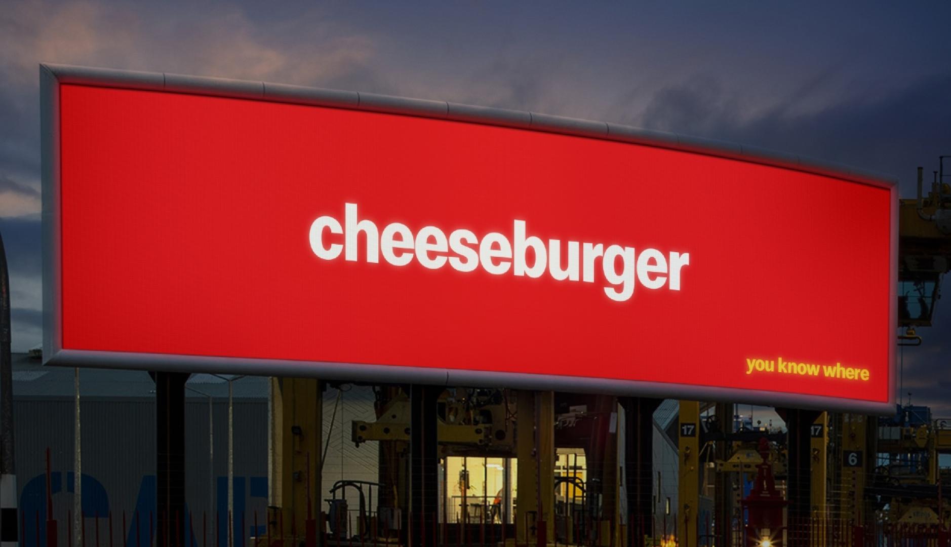 Una valla de publicidad con fondo rojo y escrito cheeseburger en blanco