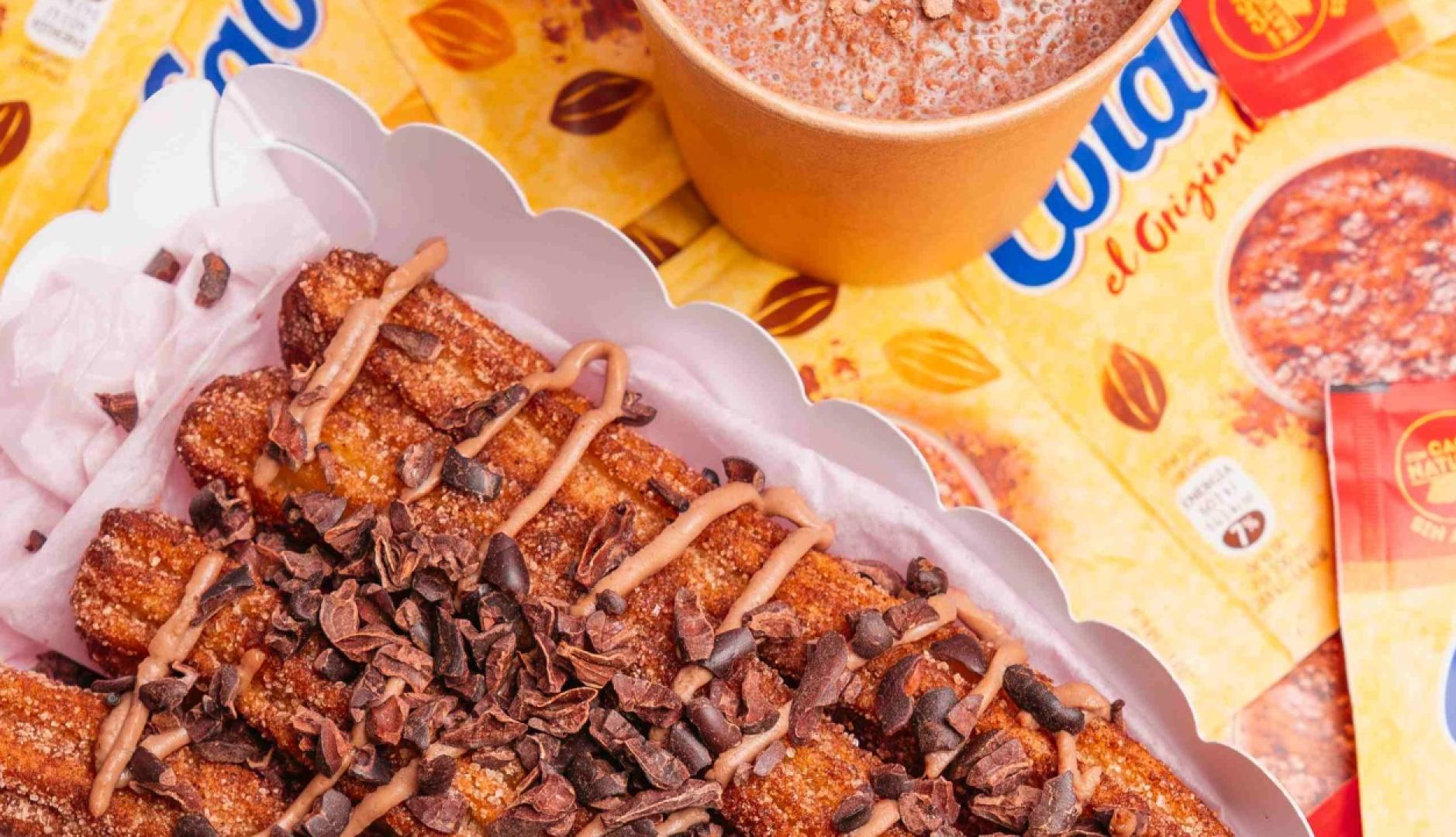 Un bodegón de churros con un vaso de ColaCao