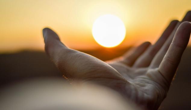 Mano alzada con sol al fondo