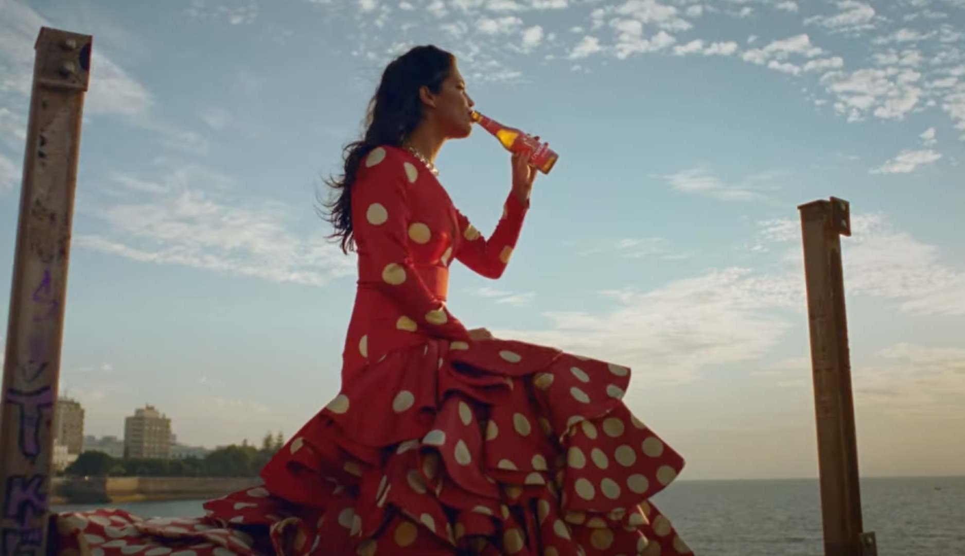 Mujer vestida de flamenca bebe botellín de Cruzcampo