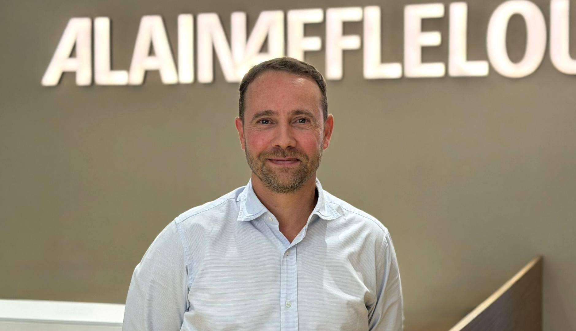 Un plano medio de Jon Mielgo y el logotipo de Alain Afflelou detrás