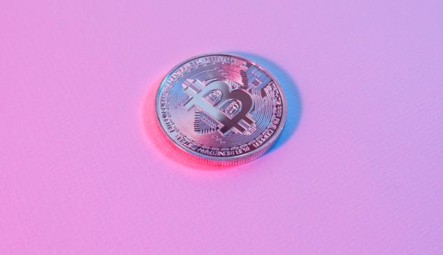 Moneda con símbolo de bitcoin sobre fondo rosa