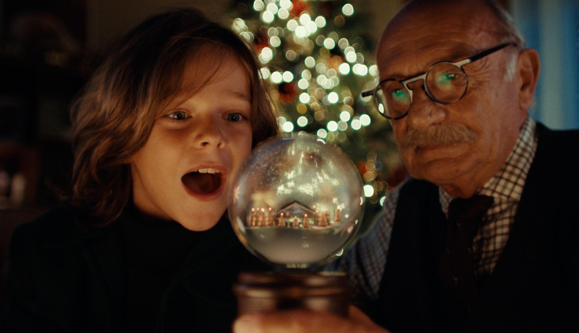 Un abuelo y su nievo miran una bola de Navidad