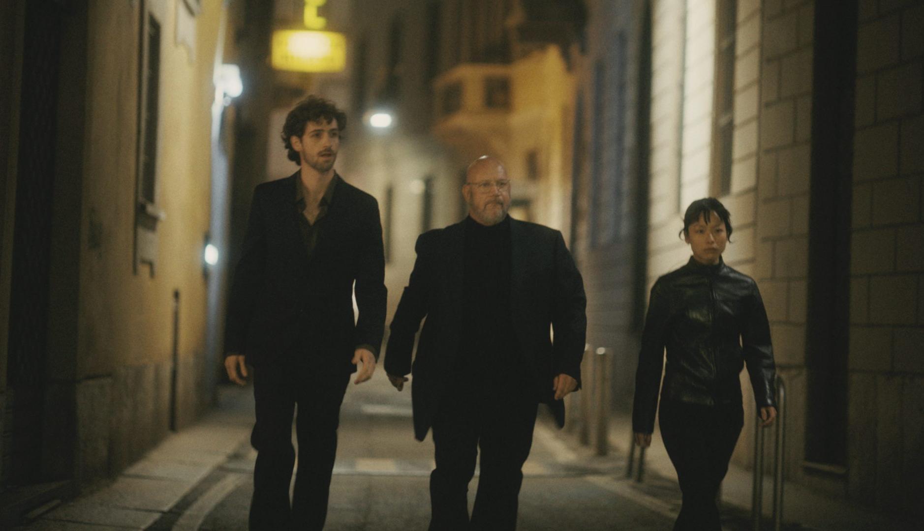 Tres personas vestidas de negro andando por la calle de noche