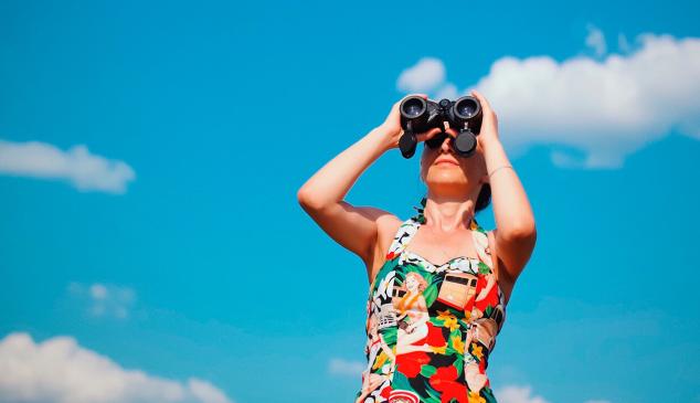 Mujer mirando por prismáticos con vestido de colores