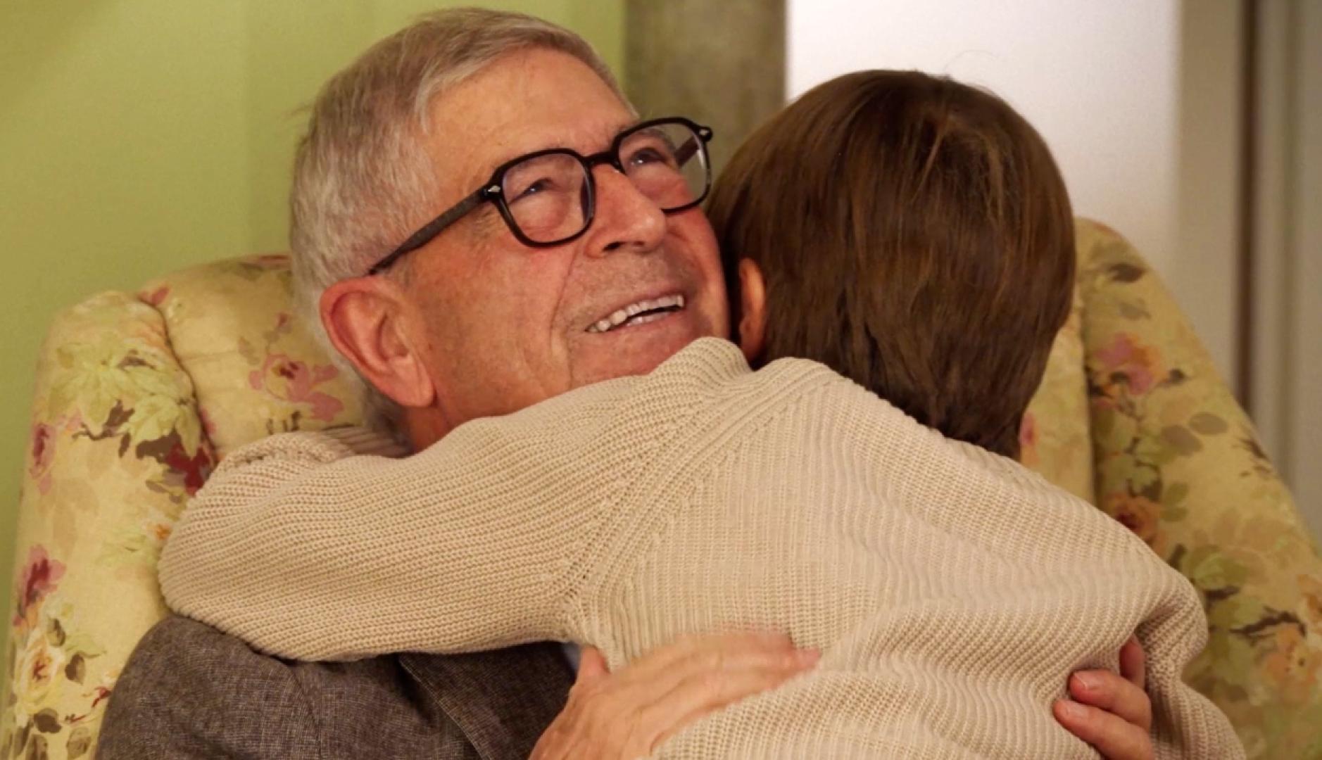 Un abuelo abrazando a su nieto pequeño en el sillón