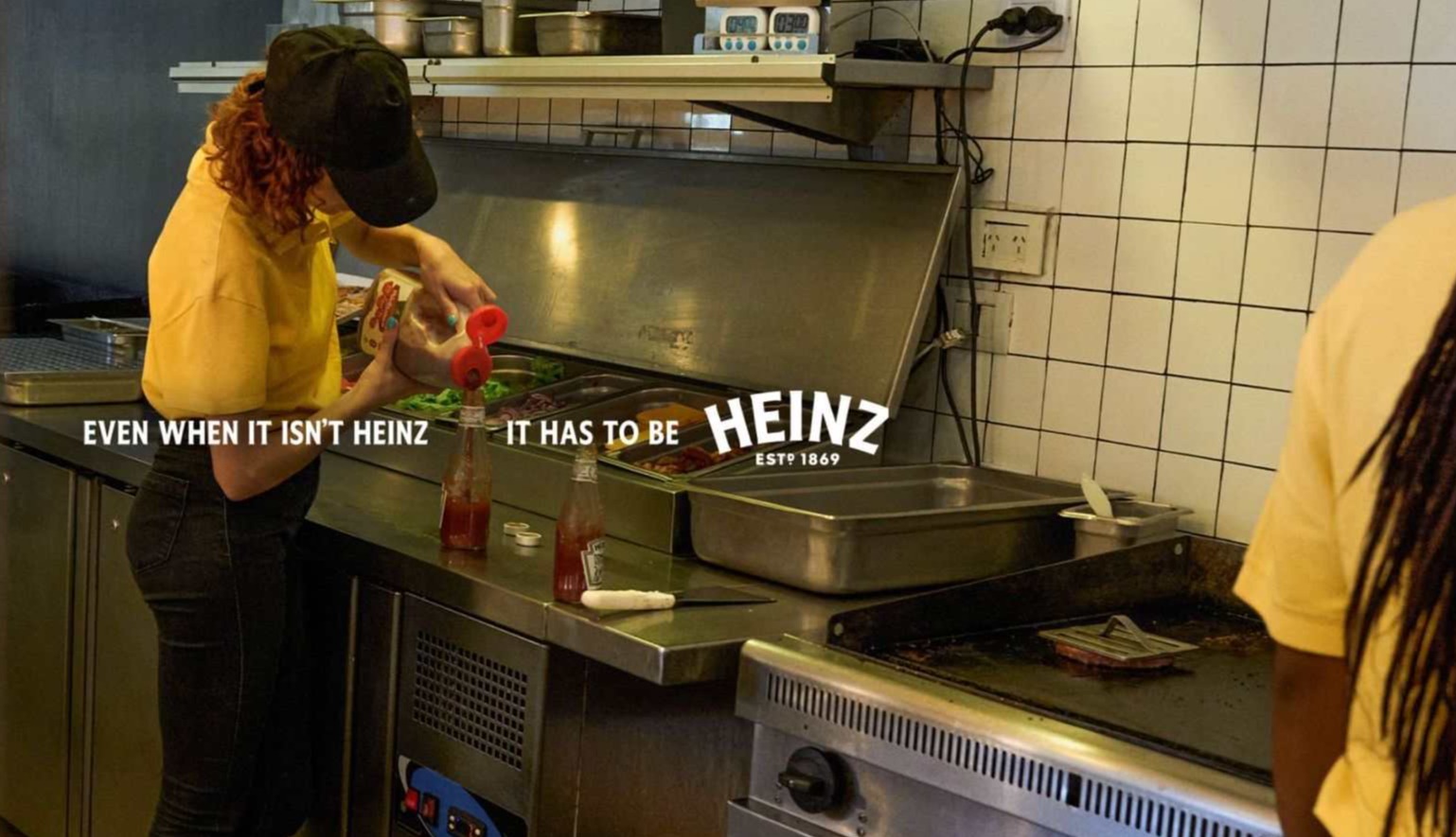 camarero rellenando un bote de heinz con otro ketchup