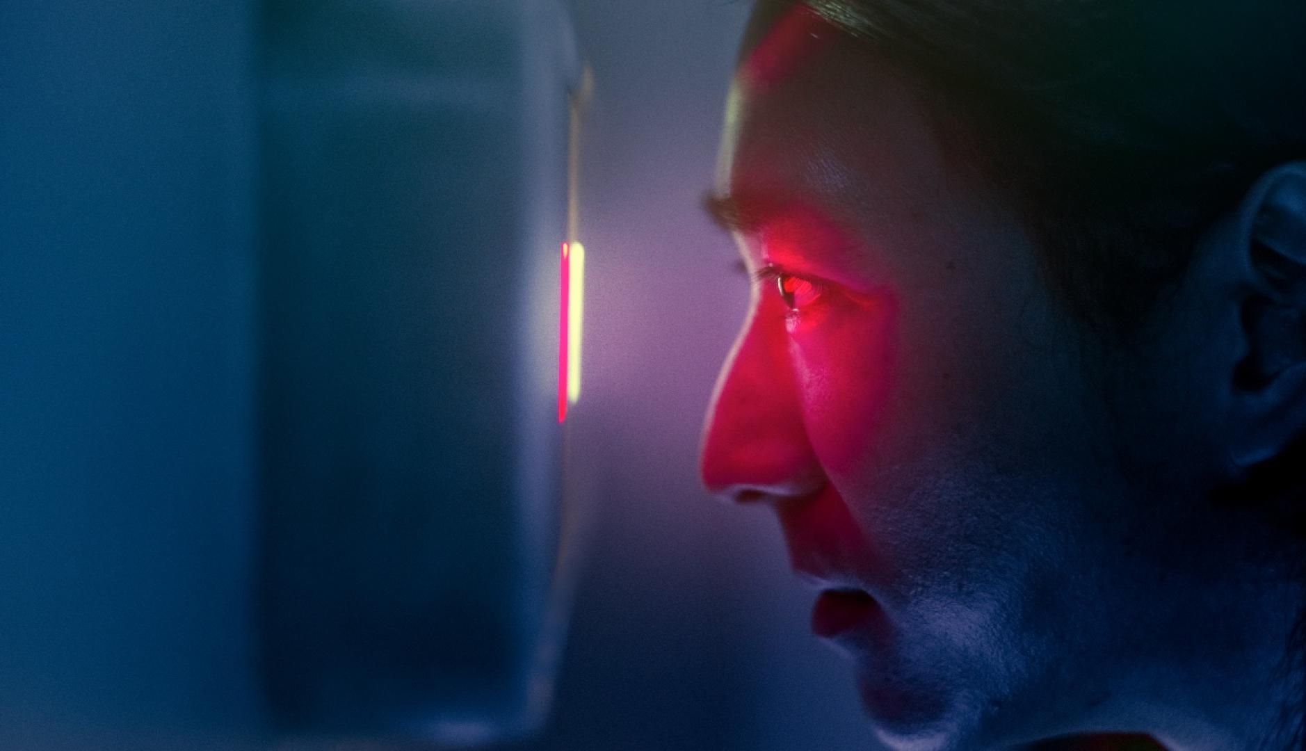Un hombre mirando por una mirilla digital con luz roja
