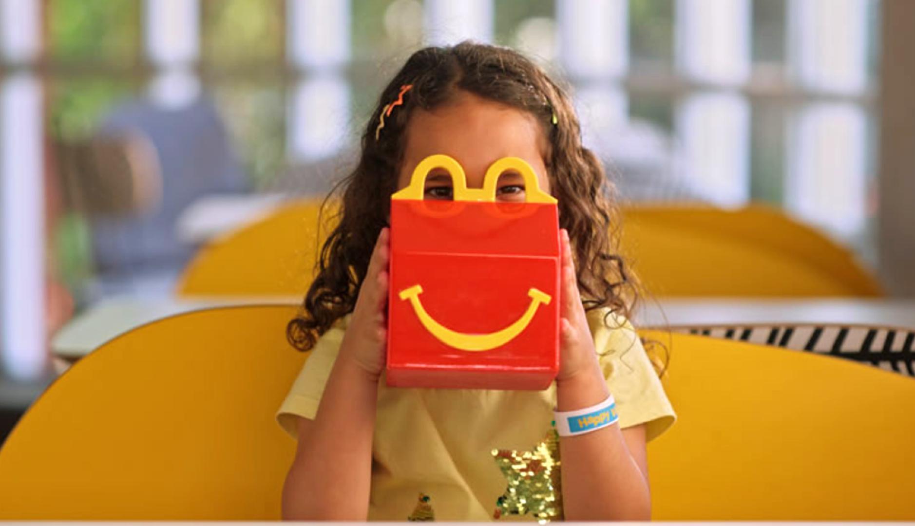 Una niña mirando por los arcos amarillos de la caja del Happy Meal