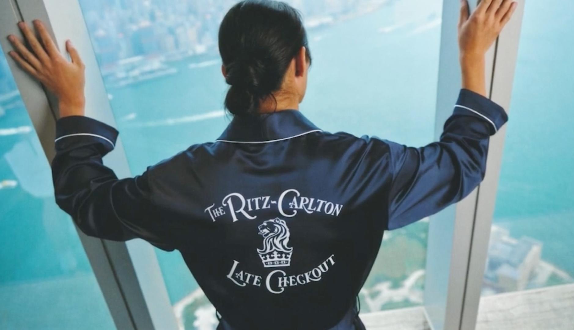 una mujer mira por la ventana con la bata del ritz carlton late checkout