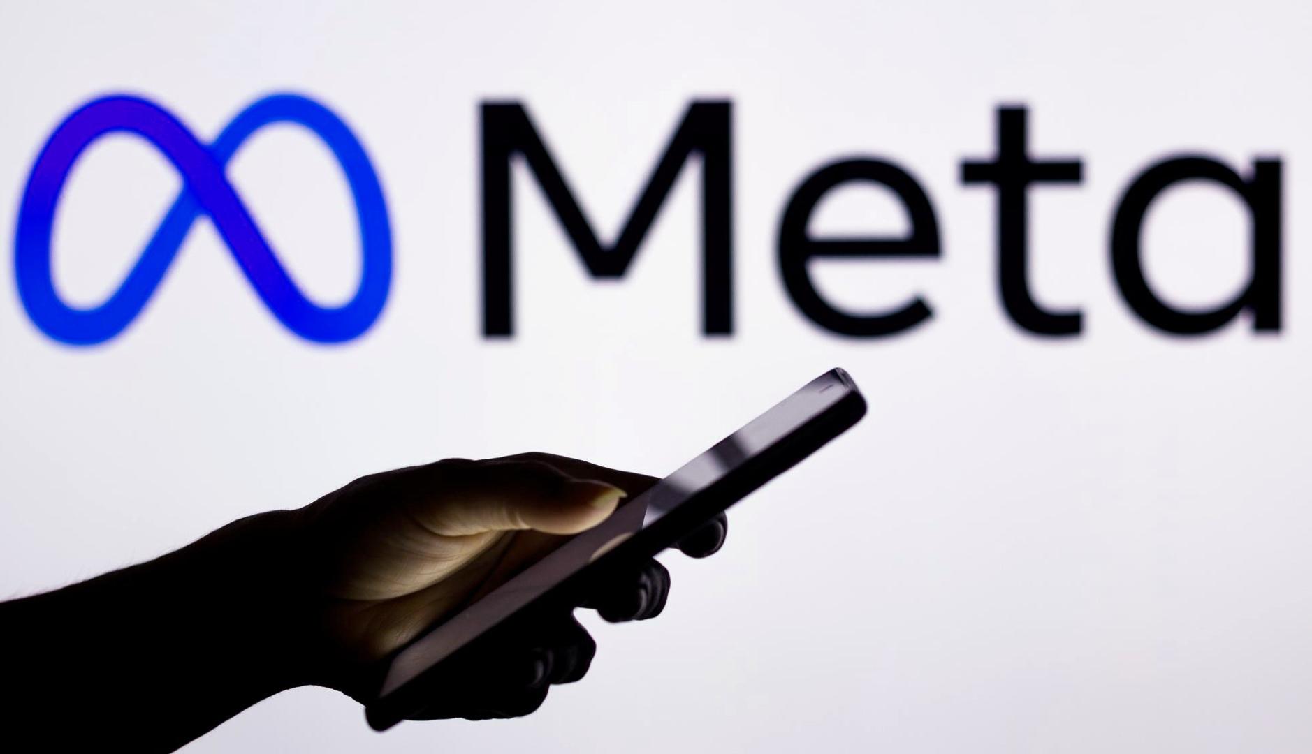 Mano sujetando un móvil con el logo de Meta detrás