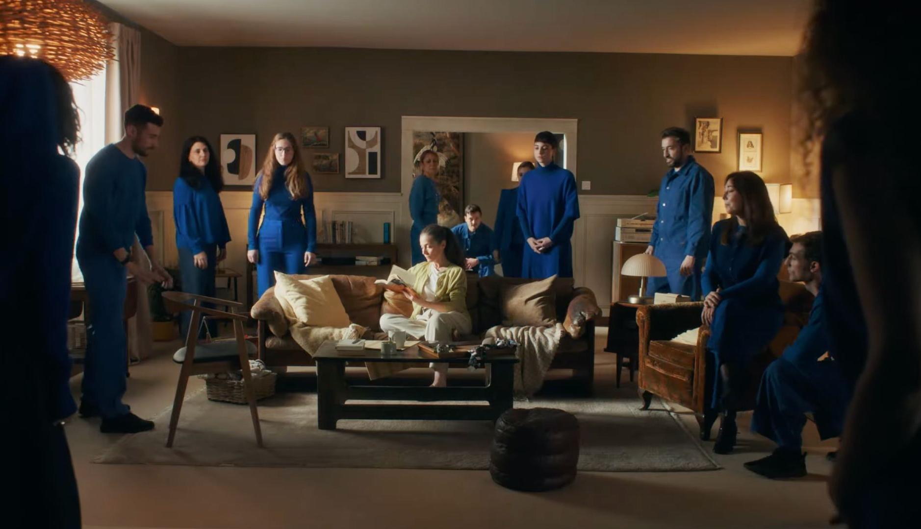 Personas vestidas de azul en torno a una mujer sentada en el sofá