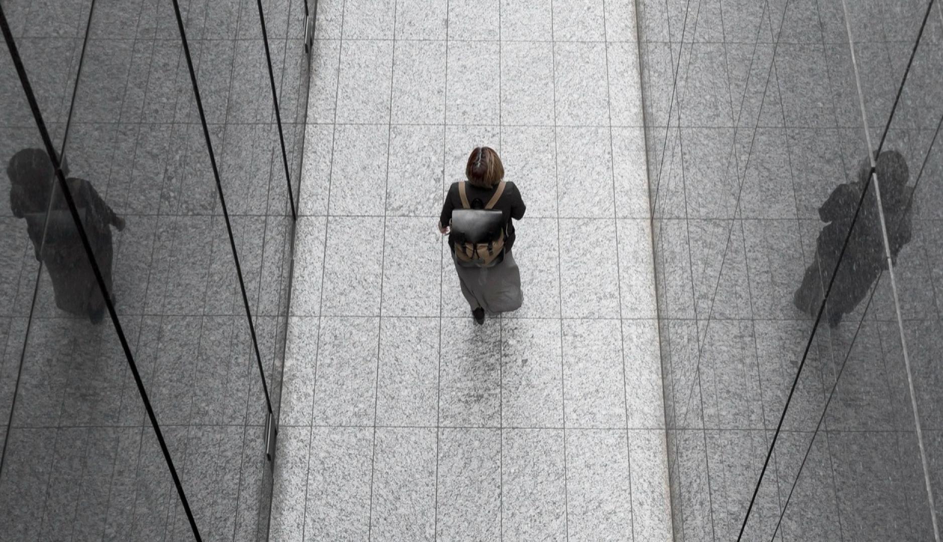 Una mujer caminando por un pasillo de espejos con una mochila de trabajo