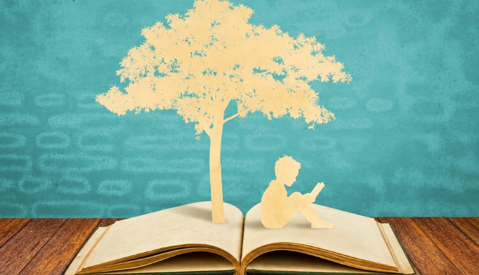 Un recorte de papel que sale de un libro y muestra la silueta de un árbol y un niño sentado leyendo
