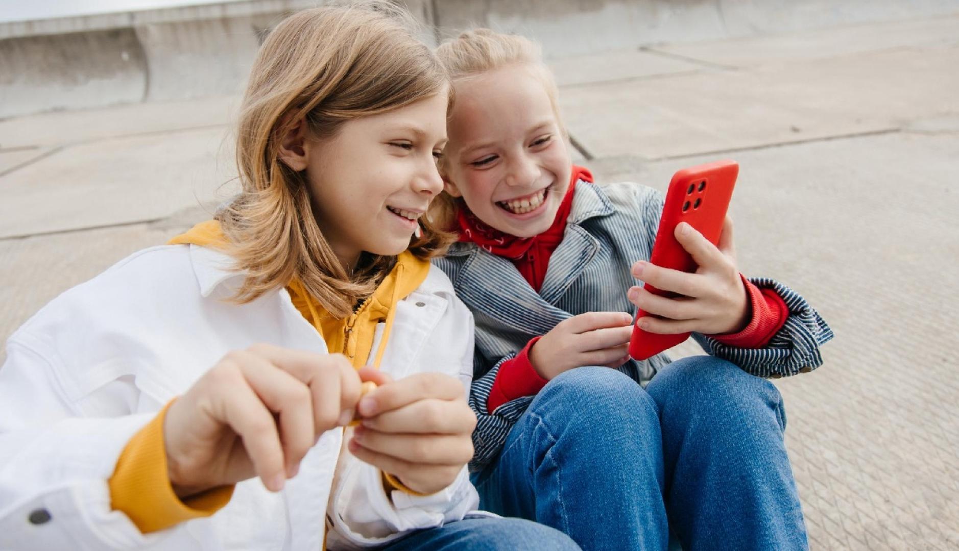 Dos niños mirando un smartphone sonriendo