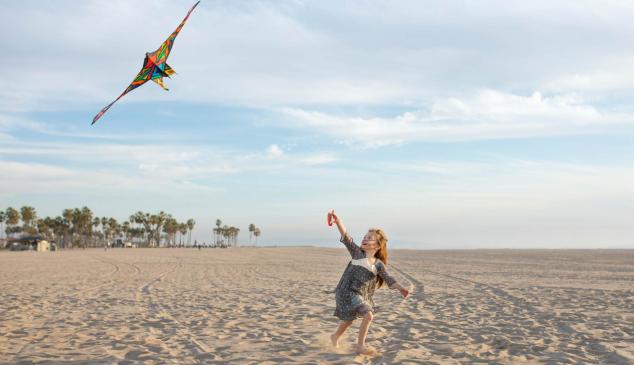 Niña volando una cometa en la playa