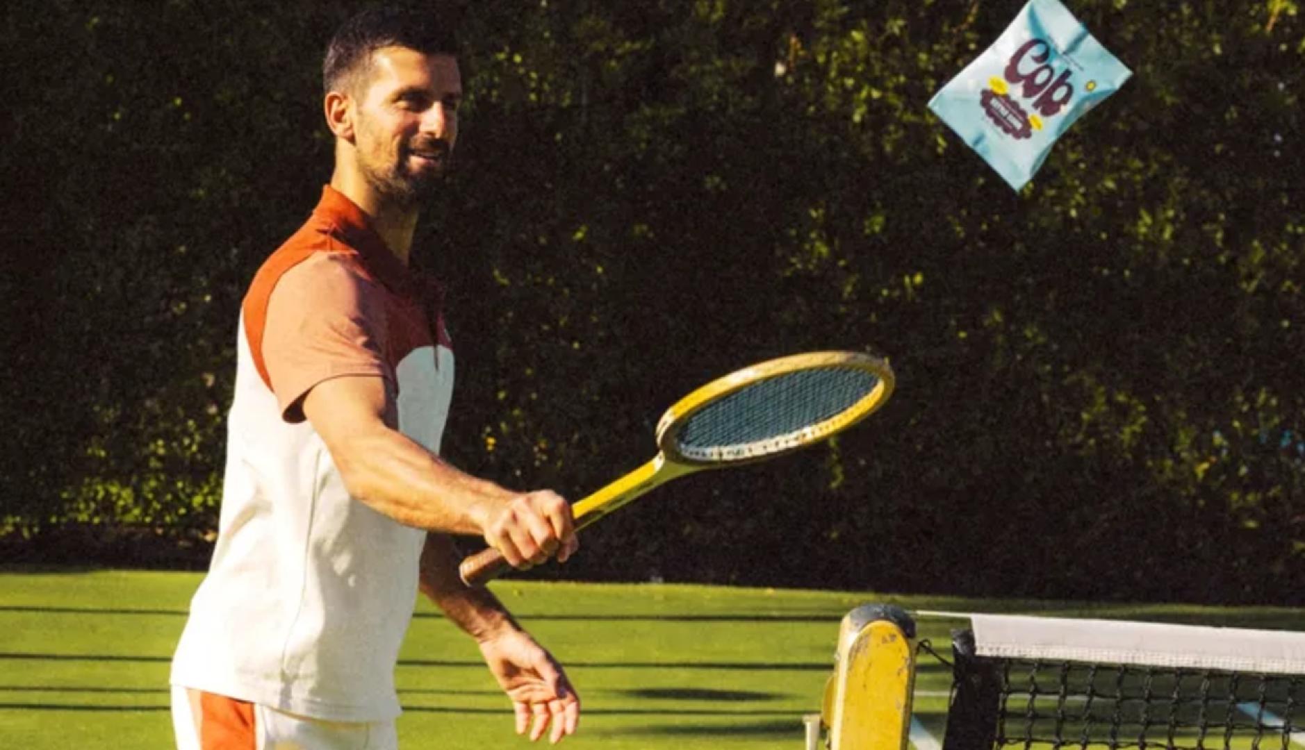 Novak Djokovic levantando una bolsa de Cob con una raqueta antigua de tenis